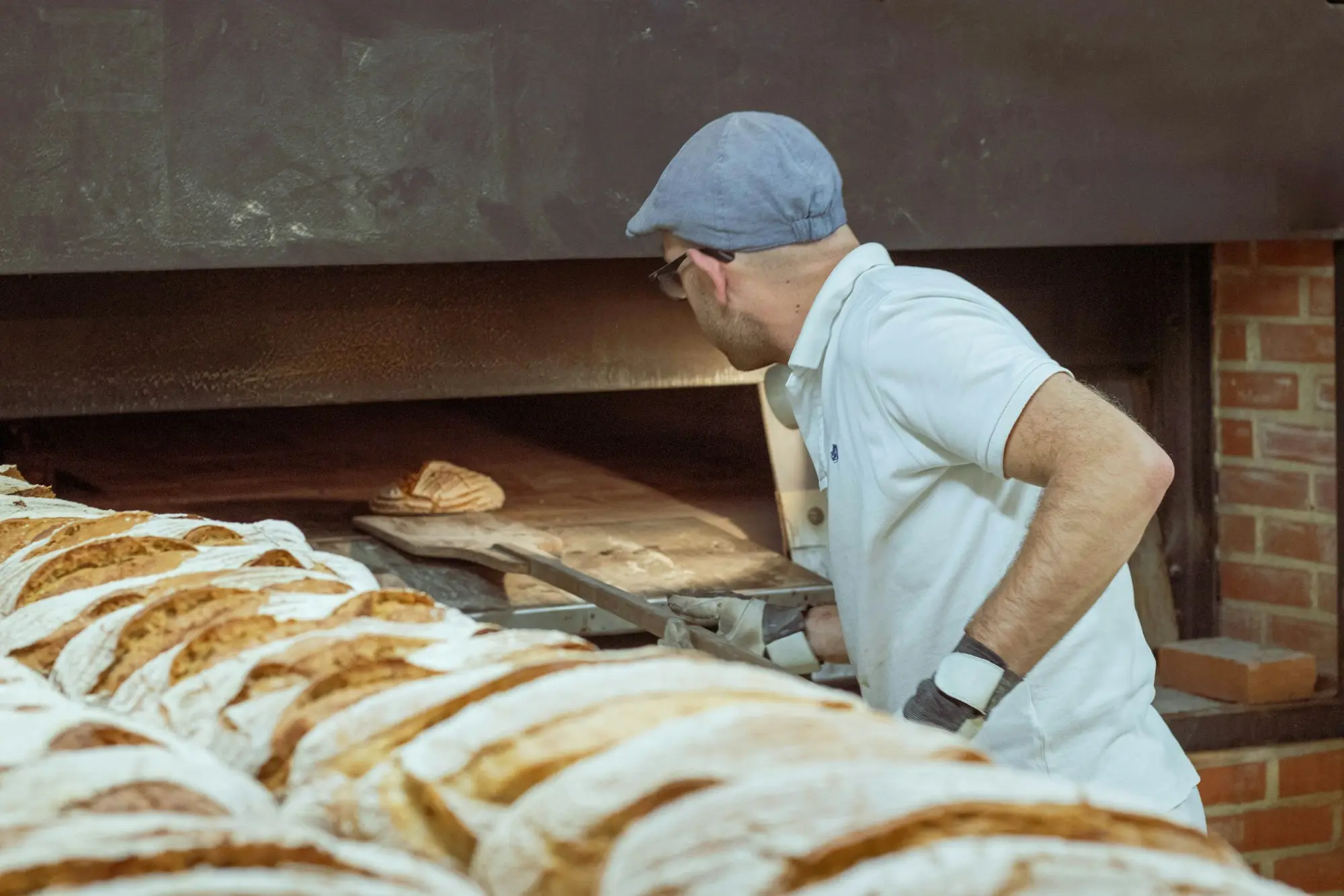 Baker loading bread into a deck oven early in the morning